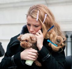 a woman holding a dog while talking on the phone