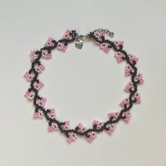 a pink and black beaded bracelet on a white surface