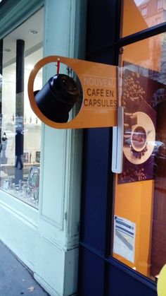 a coffee shop with an orange sign hanging from the front window and a black lamp on the outside