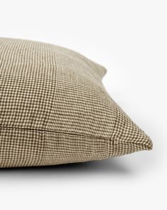 a brown and white checkered pillow on a white background