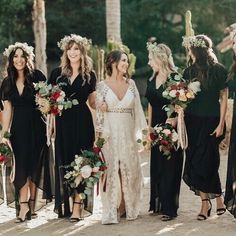 a group of women standing next to each other wearing black dresses and holding bouquets