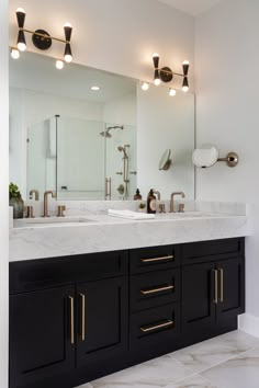 a bathroom with two sinks, mirrors and lights on the wall above them is shown