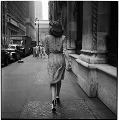 a woman is walking down the street with her hand in her pocket and wearing a polka dot dress