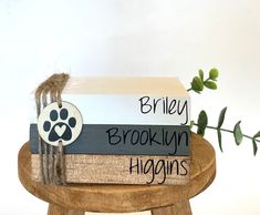 a stack of books sitting on top of a wooden stool next to a green plant