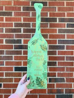 a hand holding up a green bottle with the words happy holidays written on it in front of a brick wall