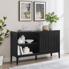 a black cabinet with two pictures on the wall above it and a rug in front of it