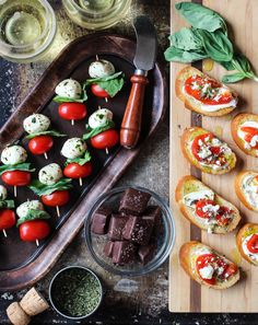 an assortment of appetizers are displayed on a cutting board next to other food items