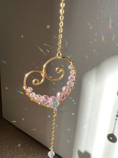 a gold necklace with pink crystals hanging from it's side on a white wall