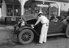 an old black and white photo of two men working on a car