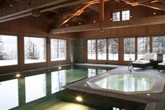 a large indoor swimming pool in the middle of a room with glass doors and windows