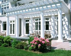 a white house with columns and flowers in the foreground, on a sunny day