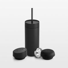 an image of a black cup next to two silver objects on a white surface with one in the middle