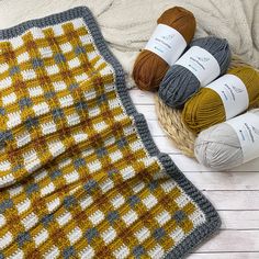 several balls of yarn sitting on top of a basket next to a crocheted blanket