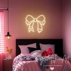 a bedroom with pink walls and a bow on the wall above the bed is lit by neon lights