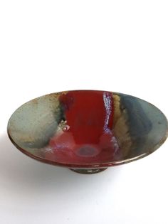 a red and gray bowl sitting on top of a white table