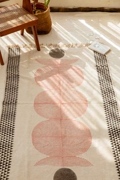 an area rug with circles on it in the middle of a room next to two chairs and a potted plant