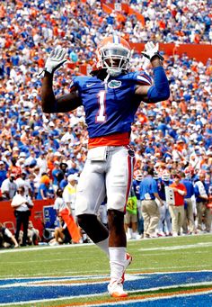 a football player is running on the field with his arms in the air as he celebrates