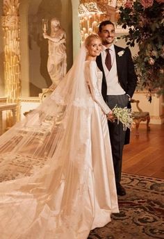 a bride and groom posing for a photo in front of a wedding dress on display