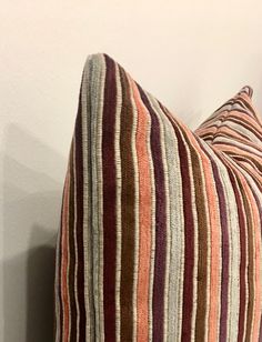 a striped pillow sitting on top of a white wall