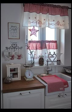 a kitchen with white cabinets and red checkered curtains