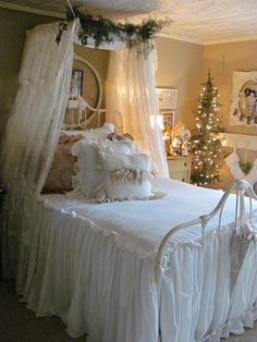 a white bed sitting in a bedroom next to a christmas tree