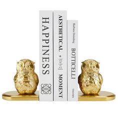 two gold owls sitting on top of each other in front of a white bookcase