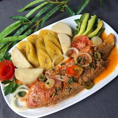 a white plate topped with fish and veggies on top of a black table