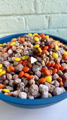 a blue bowl filled with candy corn and chocolate chip cookies next to a white brick wall