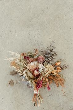 an arrangement of dried flowers and leaves on the ground