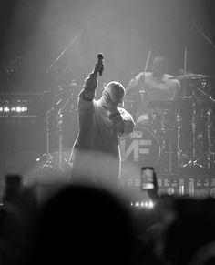 a man standing on top of a stage holding a guitar in front of his face