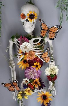 a skeleton is surrounded by flowers and butterflies