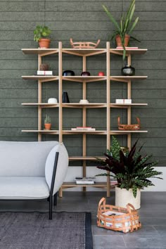 a white couch sitting next to a wooden shelf filled with potted plants