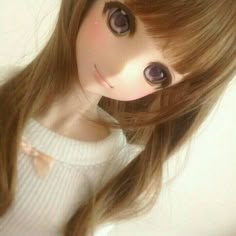 a close up of a doll with long brown hair and big blue eyes, wearing a white sweater