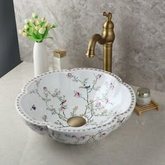 a bathroom sink with flowers on it and a faucet in the corner next to it