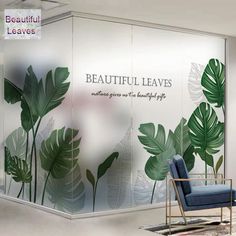 a room with a chair and some plants on the wall behind glass walls that say beautiful leaves