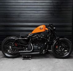 an orange and black motorcycle parked in front of a garage door