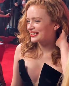 a close up of a person wearing a black dress and smiling at someone behind her