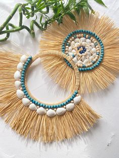 two pieces of straw with beads and shells on them are laying next to a plant