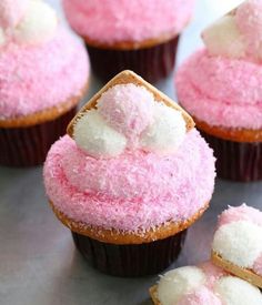 several cupcakes with pink frosting and marshmallows on the top