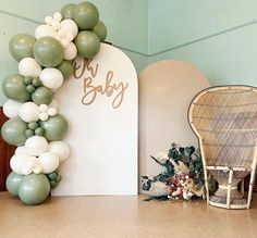 a balloon arch is decorated with green and white balloons for a baby's first birthday