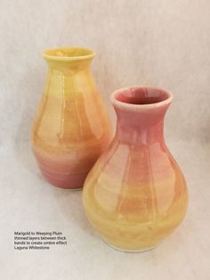 two yellow and pink vases sitting next to each other on a white tablecloth