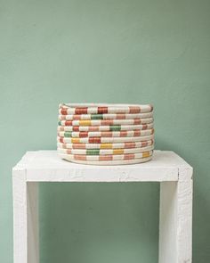 a stack of woven baskets sitting on top of a white table next to a green wall