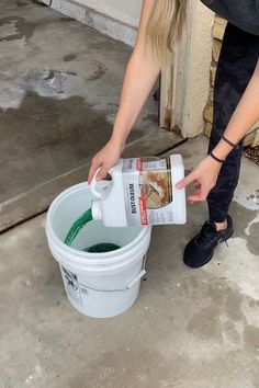 a woman is pouring water into a bucket