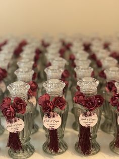 many small glass bottles with red flowers in them