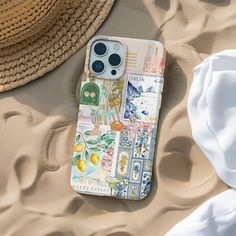 an iphone case sitting on top of sand next to a straw hat