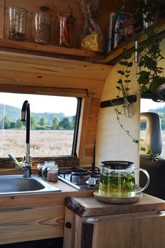 a kitchen area with a sink, stove top and window in the back ground next to a potted plant