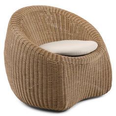 a brown wicker chair with a white pillow on it's backrest and seat cushion