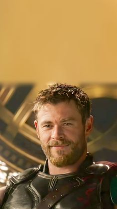 a man with a beard and leather armor on posing for a photo in front of a golden background