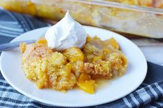 a white plate topped with fruit cobbler next to a casserole dish