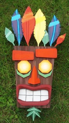 a wooden mask sitting on top of green grass